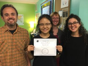 Smiling teachers with student holding her certificate of completion