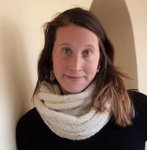 A headshot of a woman with long hair and a white scarf
