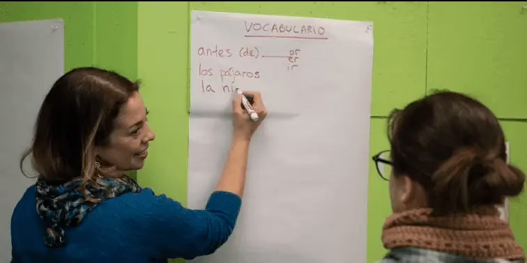 Teacher writing on newsprint with student looking on.