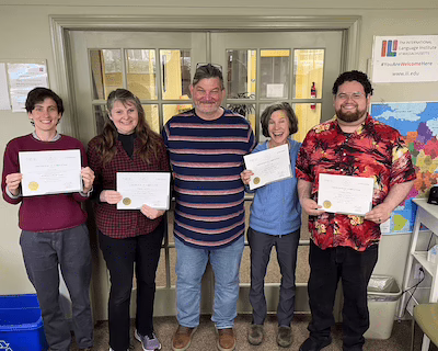 Three TESOL graduates holding their certificates and smiling.