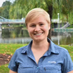 Woman smiling next to a lake.