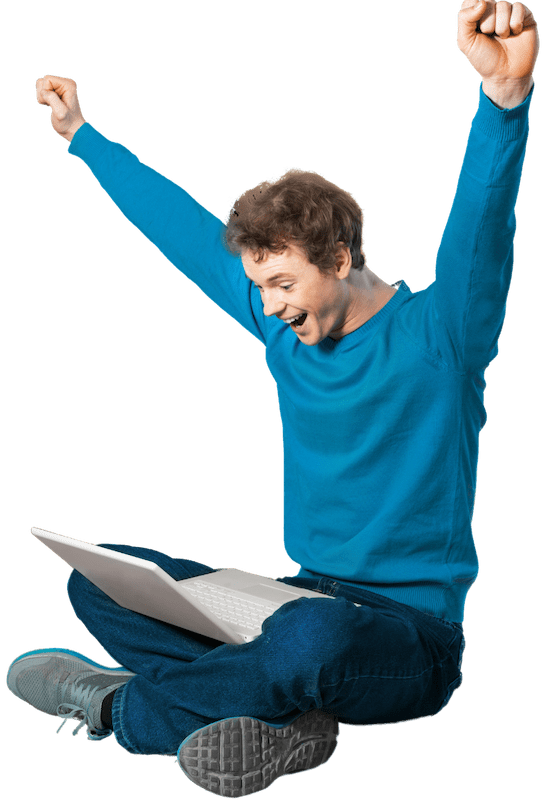 A man sitting crossed leg with an open laptop with his arms raised and very happy.