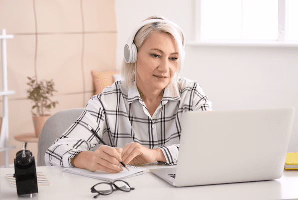 A woman on a computer with headphones.