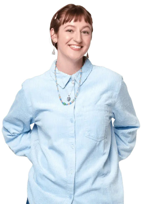 A person with short hair wearing a blue shirt and fun jewelry, looking stylish and confident.