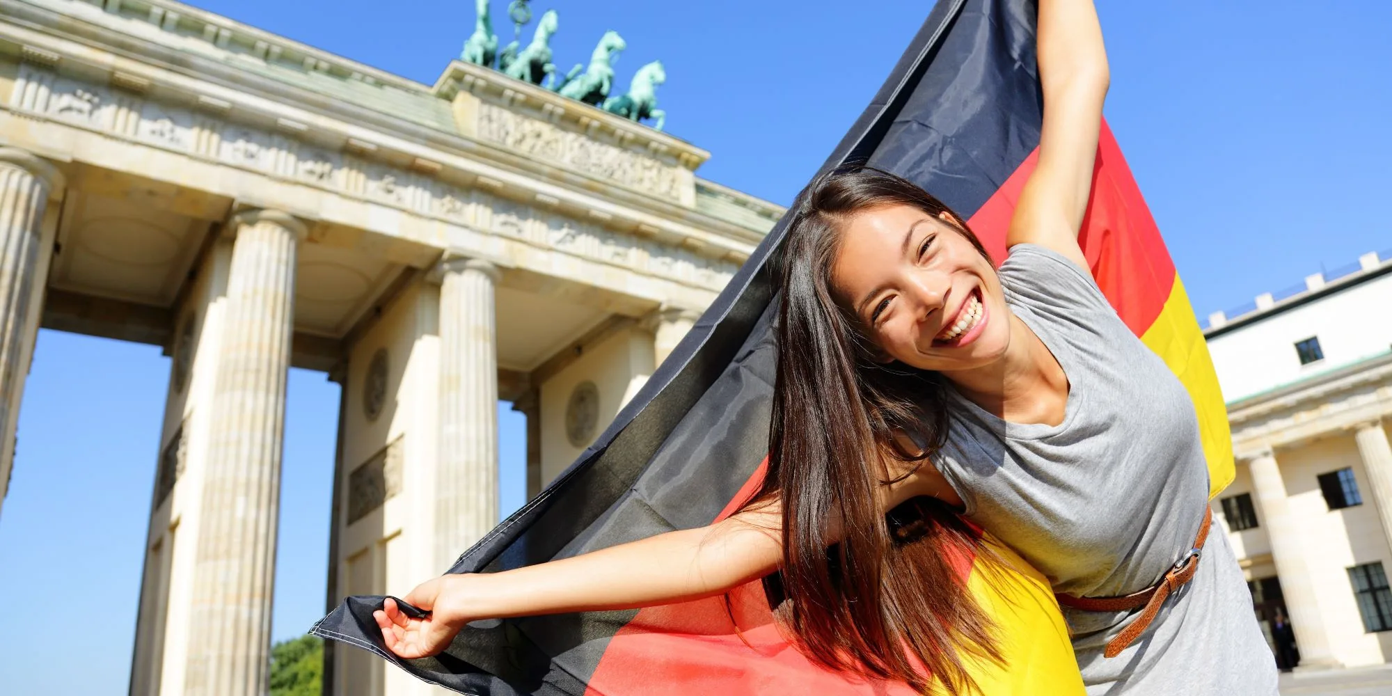 A woman smiling and holding a German flag.