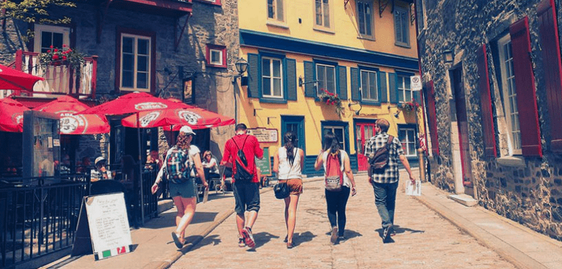 Five language Travel French students exploring a cobbled street of shops and cafes in Québec City.