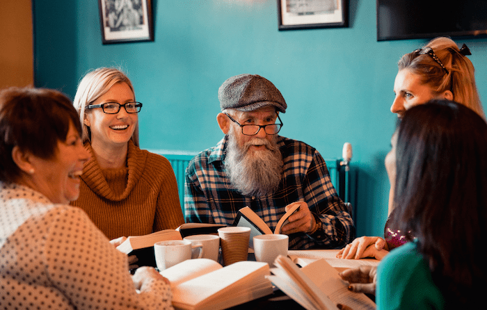 A group of adults sitting around a table discussing a book.