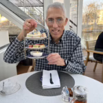 A man smiling holding a tray of desserts.