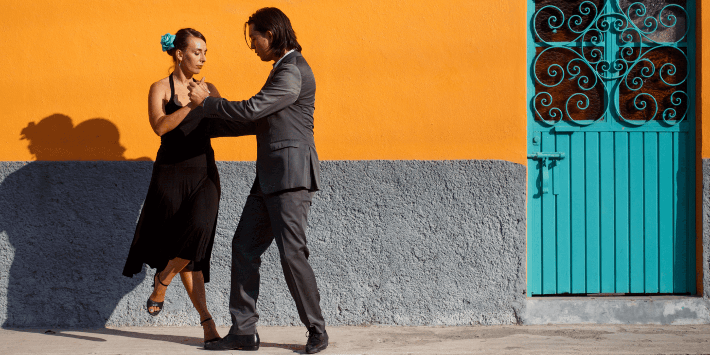 Two people dancing tango on a sidewalk.