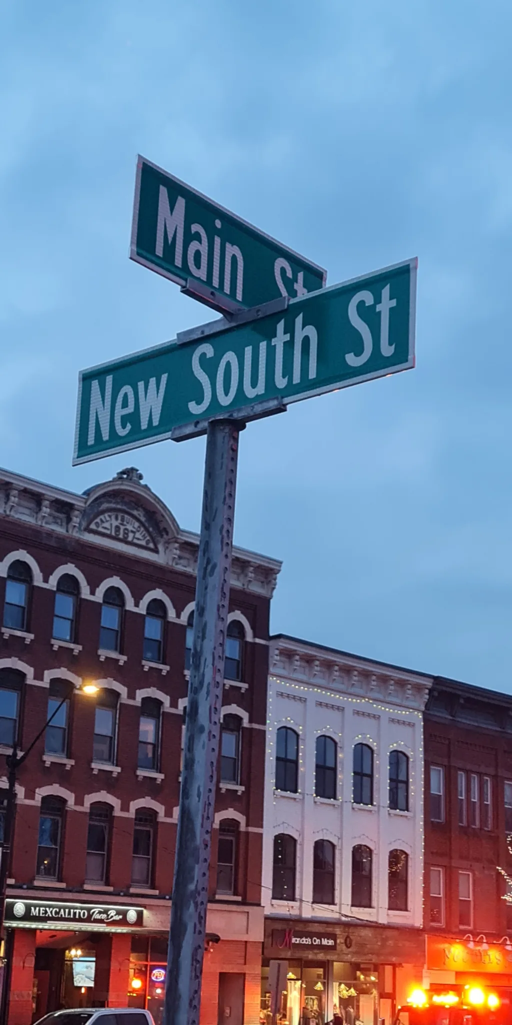 Two stacked street signs that say Main St. and New South St.