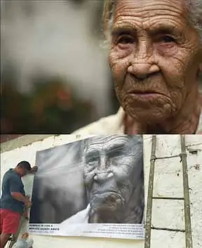 Two images stacked. The bottom image is a man putting up a poster of a woman and the top image is the woman in the poster.