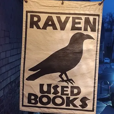 A cloth sign with a clack bird that says Raven Used Books.
