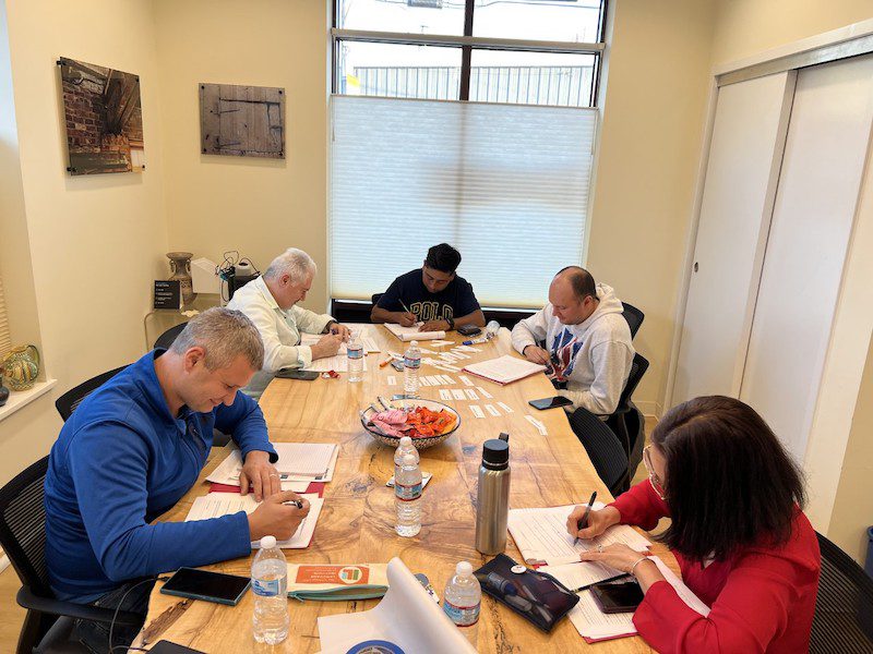 A group of people sitting at a table, doing a writing activity.