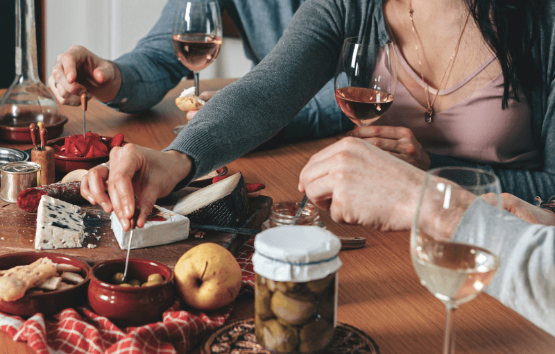 A group of friends enjoying wine and cheese while sharing delicious tapas