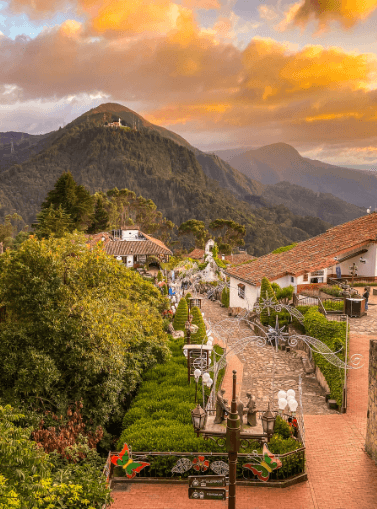 Scenic view of a charming village nestled in the mountains, framed by majestic peaks and vibrant nature.