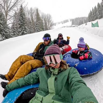 Four people tubing on a snowy hill.