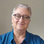 Portrait of a woman wearing a blue shirt and glasses smiling.