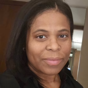 A woman with straight black hair in a black shirt, smiling softly while facing the camera.