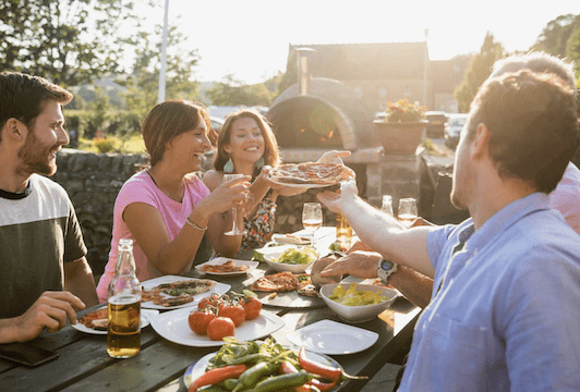 Five adults sharing a meal at an outdoor cafe.