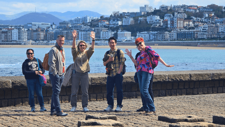 a group of people posing on a beach shore.