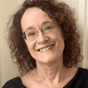 a woman with curly hair wearing glasses smiling