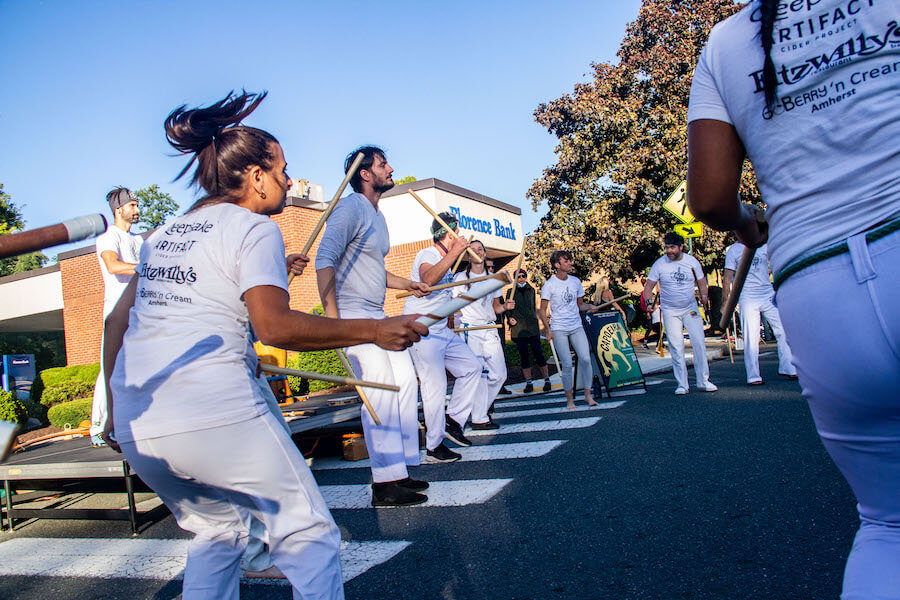 a group of people doing brazilian martial arts on the street during a local celebration.