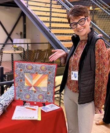 A woman showing a quilt piece.
