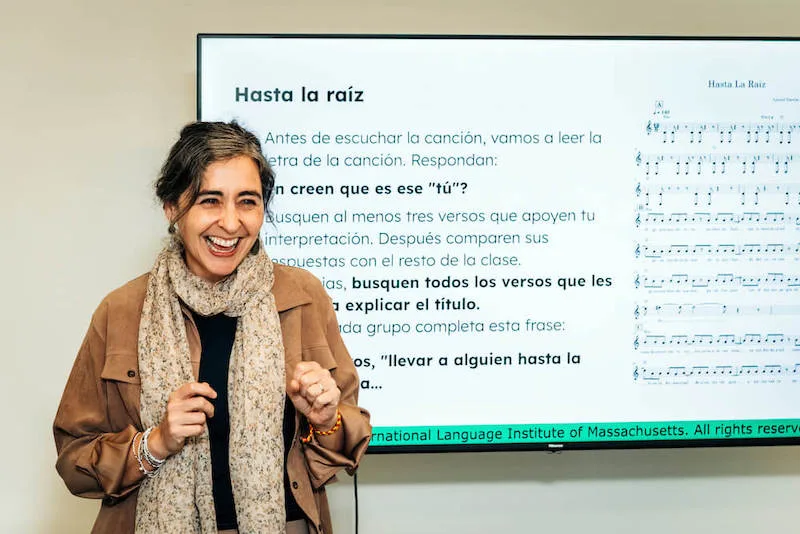 A smiling woman standing in front of a tv with music lyrics on the screen